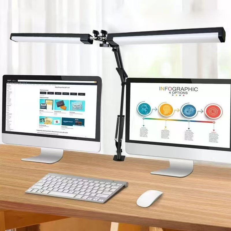 Desk setup with two computer monitors, keyboard, and mouse under a dual arm desk lamp.