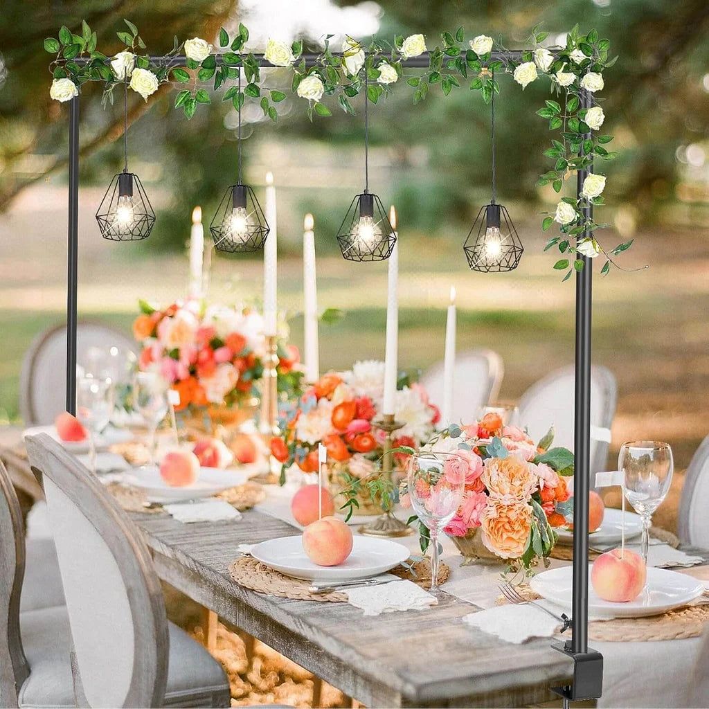 Decorative outdoor table setting with floral arch, candles, and fruit.