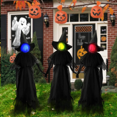 Three illuminated witch figures with colorful lights in front of a Halloween-themed house.