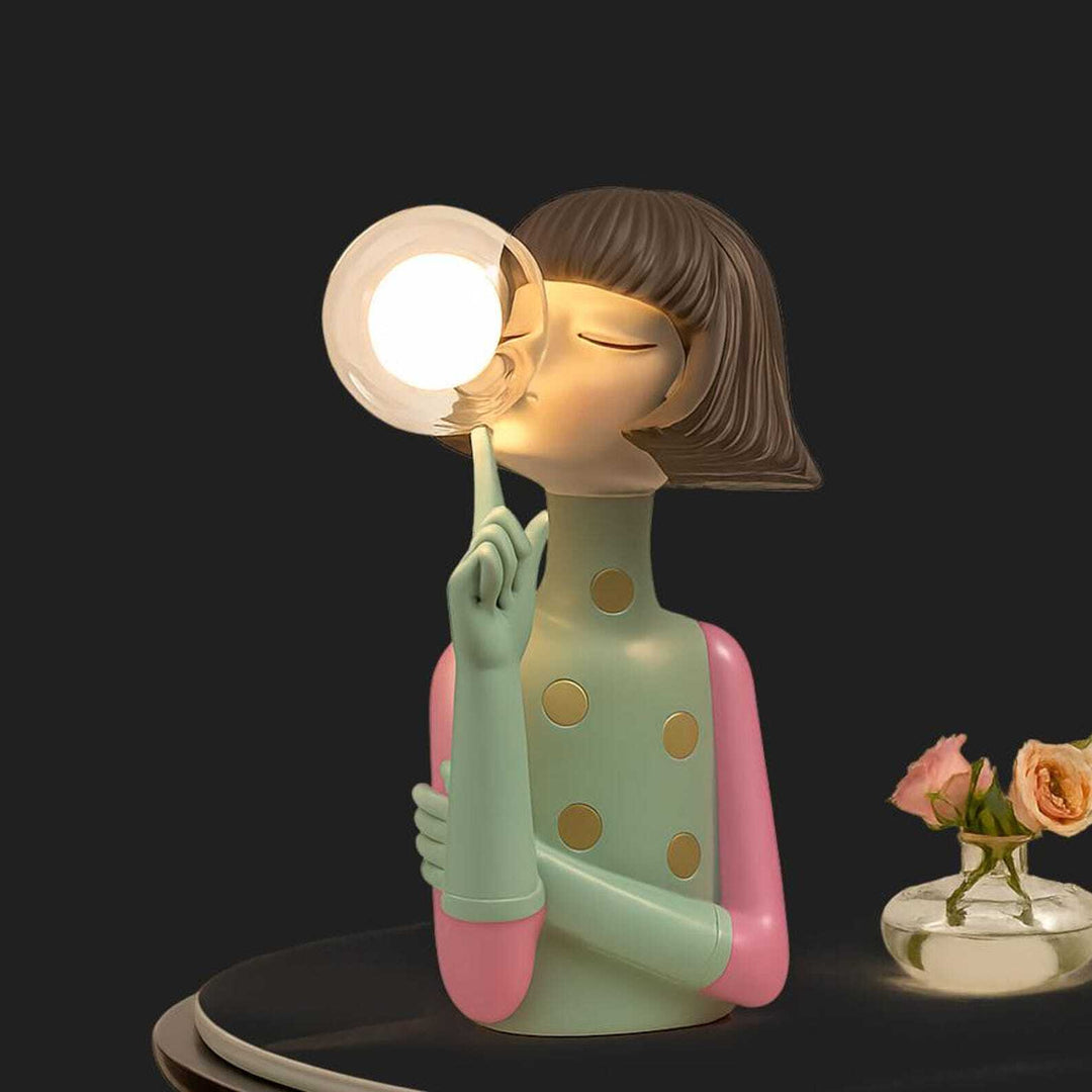 Decorative lamp shaped like a person blowing a bubble with a light bulb inside, on a dark background.