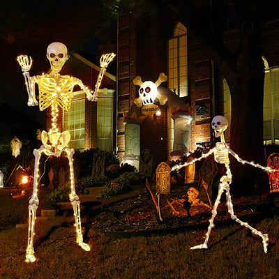 Halloween decorations including skeletons and tombstones in front of a house.